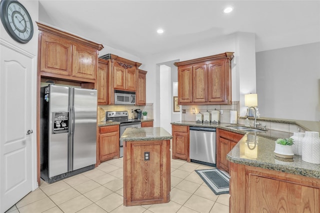kitchen with a center island, a sink, stainless steel appliances, backsplash, and stone countertops