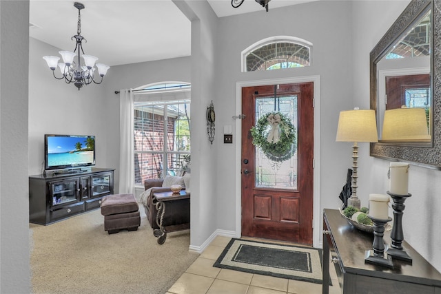foyer entrance with baseboards, light colored carpet, a notable chandelier, and plenty of natural light