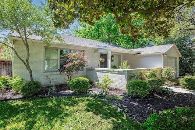 ranch-style home featuring brick siding, a front lawn, a garage, and a fenced front yard