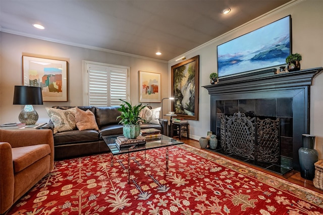 living room featuring baseboards, recessed lighting, a tiled fireplace, crown molding, and wood finished floors
