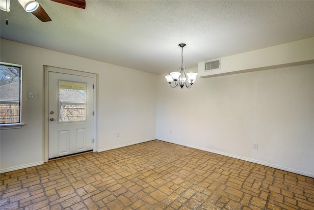 spare room with brick floor, visible vents, baseboards, and ceiling fan with notable chandelier