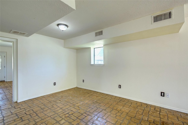 below grade area with brick floor, baseboards, and visible vents