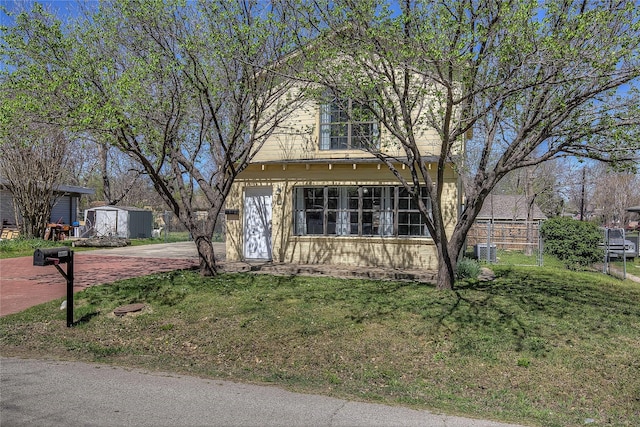 view of front of home featuring a storage shed, a front lawn, central AC unit, and an outbuilding