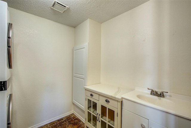 bathroom featuring vanity, visible vents, baseboards, and a textured ceiling