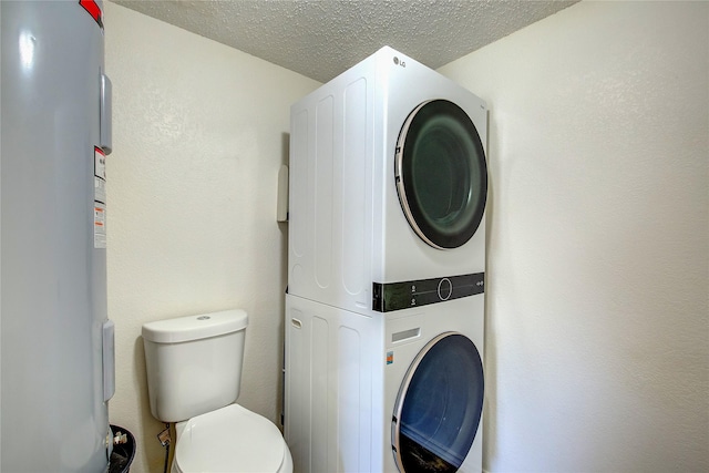 interior space with stacked washer / dryer, a textured wall, laundry area, electric water heater, and a textured ceiling