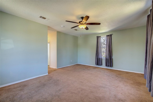 spare room featuring visible vents, baseboards, a ceiling fan, a textured ceiling, and carpet floors