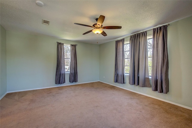 carpeted spare room with visible vents, ceiling fan, plenty of natural light, and a textured ceiling