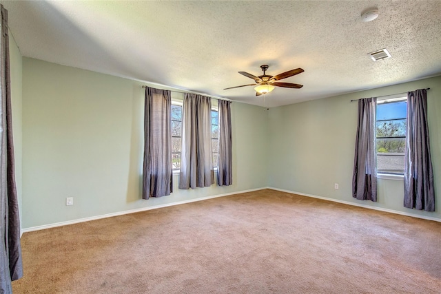 spare room with carpet, visible vents, baseboards, and ceiling fan