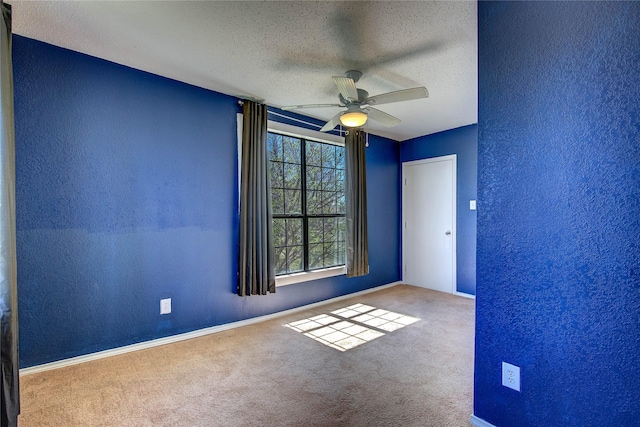 carpeted empty room featuring baseboards, a ceiling fan, a textured wall, and a textured ceiling