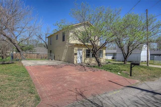 view of front facade featuring fence, decorative driveway, and a front lawn