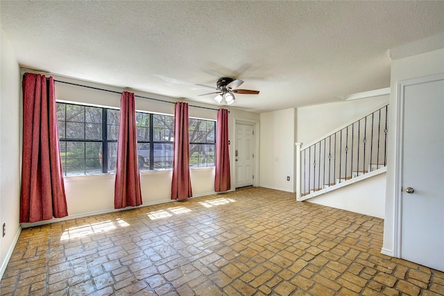spare room with stairs, brick floor, and a ceiling fan