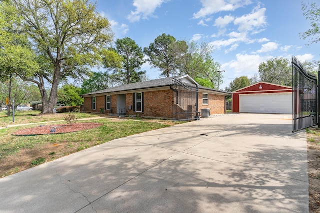ranch-style house featuring concrete driveway, a detached garage, brick siding, central AC, and an outbuilding