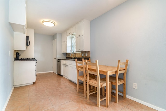 kitchen featuring a sink, dark countertops, white cabinetry, backsplash, and stainless steel dishwasher