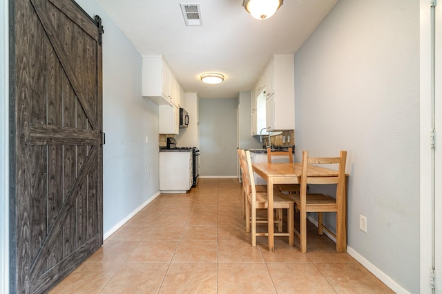 dining area with visible vents, baseboards, a barn door, and light tile patterned floors