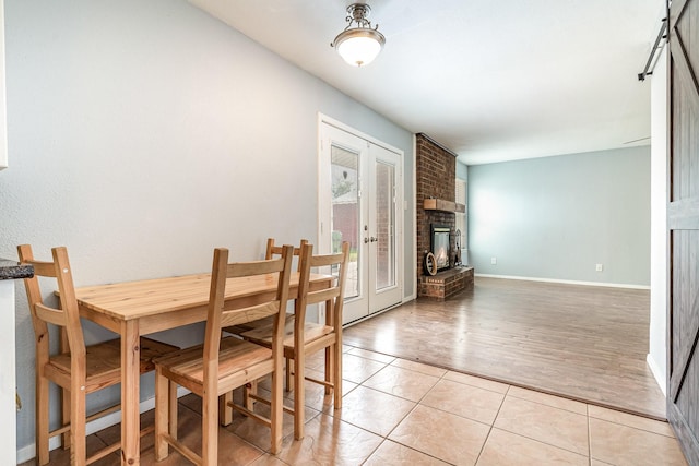 dining area with french doors, baseboards, light tile patterned flooring, and a fireplace