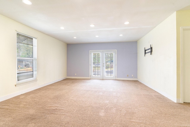 empty room with light carpet, recessed lighting, french doors, and baseboards
