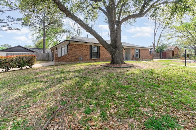 view of side of home with a yard, fence, and brick siding