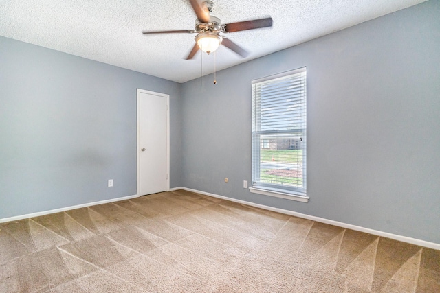 spare room featuring a textured ceiling, carpet flooring, ceiling fan, and baseboards