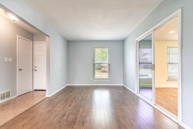 empty room featuring visible vents, baseboards, and wood finished floors