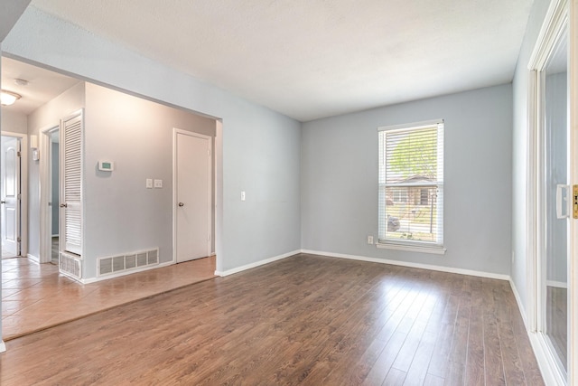 spare room with wood finished floors, baseboards, and visible vents