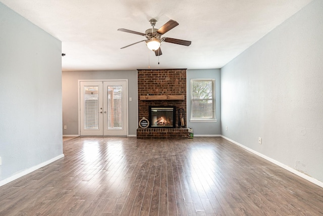 unfurnished living room featuring ceiling fan, a fireplace, french doors, baseboards, and hardwood / wood-style flooring