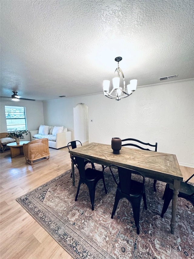 1317 N Mary St, Comanche, TX 76442 - dining area featuring a textured wall, a textured ceiling, light wood-style floors, arched walkways, and a chandelier