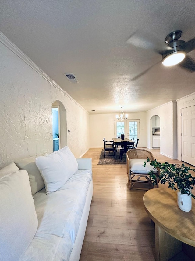 1317 N Mary St, Comanche, TX 76442 - living room featuring a textured ceiling, wood finished floors, a chandelier, arched walkways, and baseboards