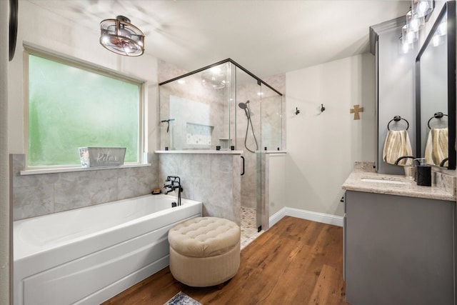 bathroom featuring a shower stall, vanity, a bath, baseboards, and wood finished floors