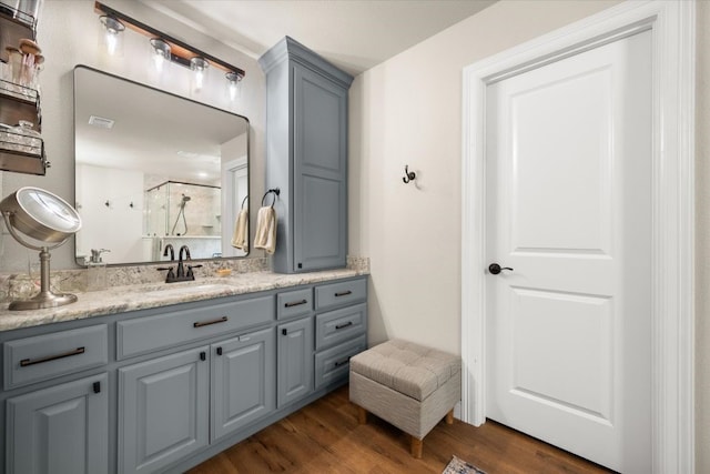 full bathroom featuring visible vents, wood finished floors, walk in shower, and vanity