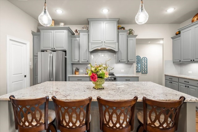 kitchen with decorative backsplash, freestanding refrigerator, a large island, gray cabinetry, and pendant lighting