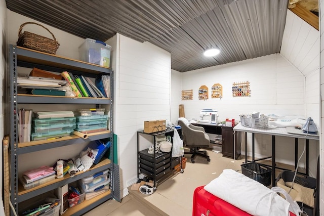 office area featuring concrete floors, wooden walls, and vaulted ceiling