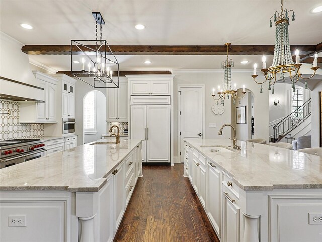 kitchen with an inviting chandelier, a sink, arched walkways, a spacious island, and high quality appliances