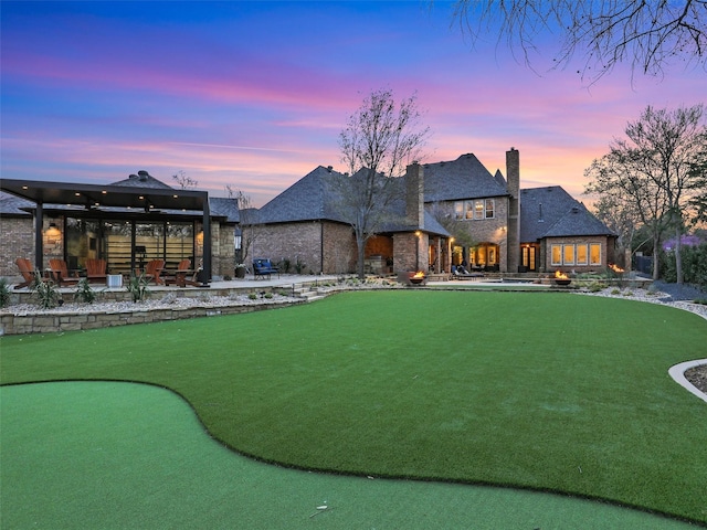 back of house with stone siding, a patio, and a chimney
