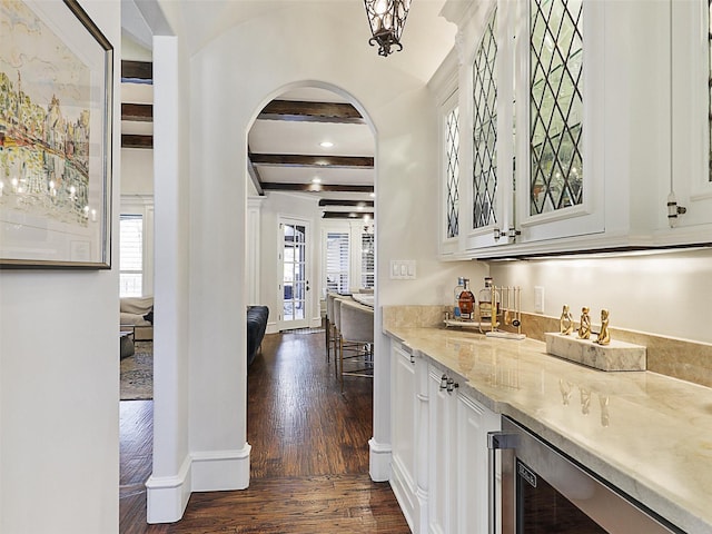 bar featuring wine cooler, a healthy amount of sunlight, a dry bar, dark wood-type flooring, and arched walkways