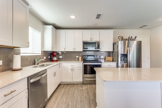 kitchen featuring appliances with stainless steel finishes, light wood-type flooring, white cabinetry, and visible vents