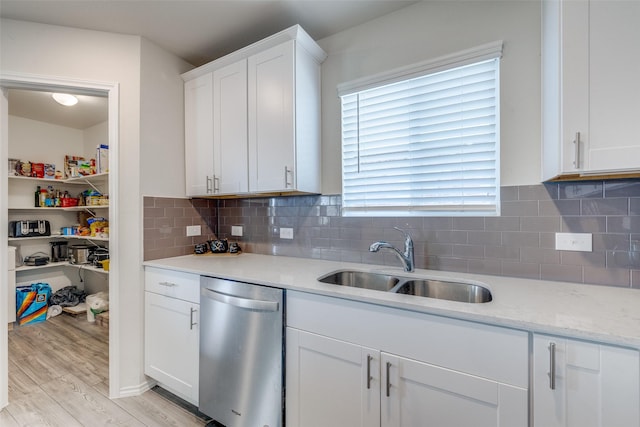 kitchen with tasteful backsplash, dishwasher, a sink, light wood-style floors, and white cabinetry