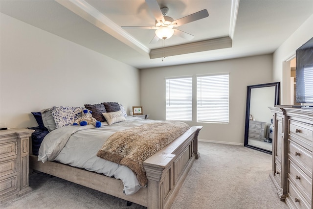 bedroom featuring crown molding, light carpet, baseboards, a raised ceiling, and a ceiling fan