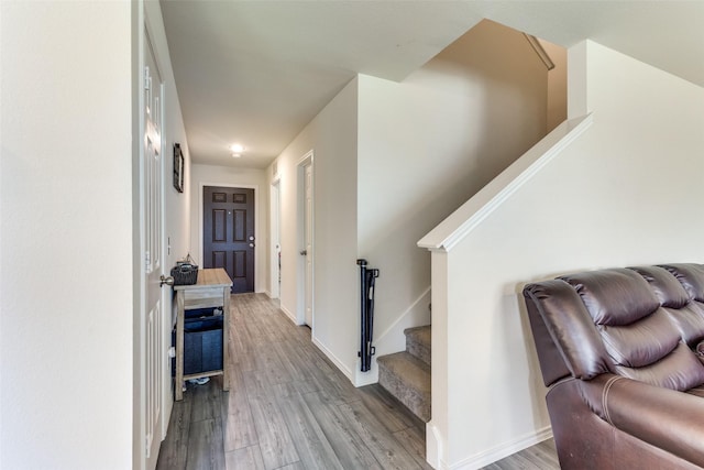 hall with baseboards, wood finished floors, and stairway