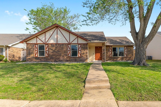 4248 Ireland Dr, The Colony, TX 75056 - tudor house featuring a shingled roof, brick siding, central AC unit, and a front lawn