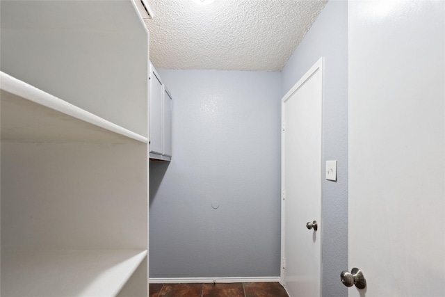 clothes washing area featuring baseboards and a textured ceiling