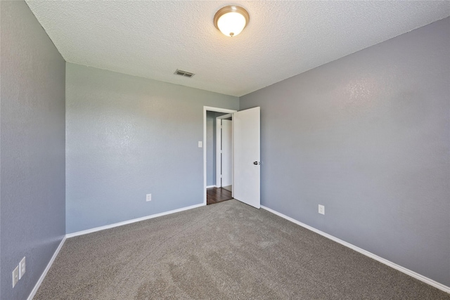 carpeted empty room featuring visible vents, baseboards, and a textured ceiling