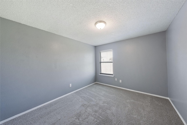 carpeted spare room with a textured ceiling and baseboards