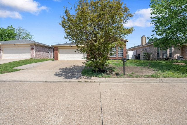 obstructed view of property with brick siding, an attached garage, a front lawn, and concrete driveway