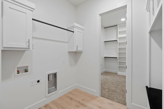 laundry area featuring hookup for a washing machine, hookup for an electric dryer, light wood finished floors, baseboards, and cabinet space