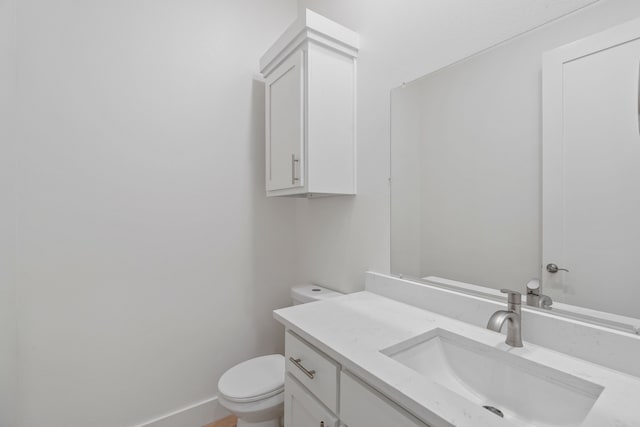 bathroom featuring toilet, vanity, and baseboards