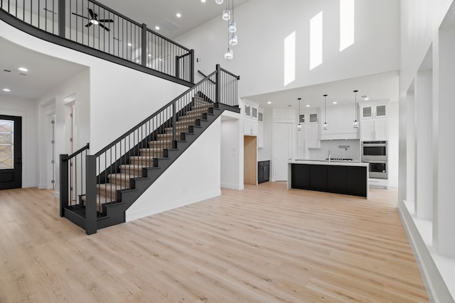 interior space with stairway, light wood finished floors, a towering ceiling, and a sink