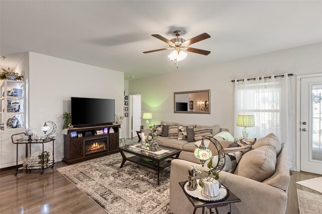 1703 Ratama Dr, Princeton, TX 75407 - living room featuring wood finished floors, a ceiling fan, and a warm lit fireplace
