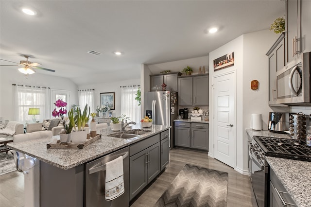 1703 Ratama Dr, Princeton, TX 75407 - kitchen with appliances with stainless steel finishes, gray cabinets, ceiling fan, a center island with sink, and light stone counters