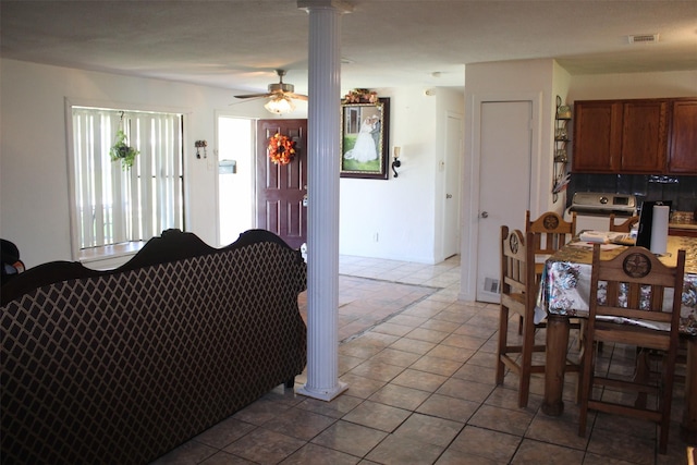 living area featuring ornate columns, a ceiling fan, tile patterned floors, and visible vents