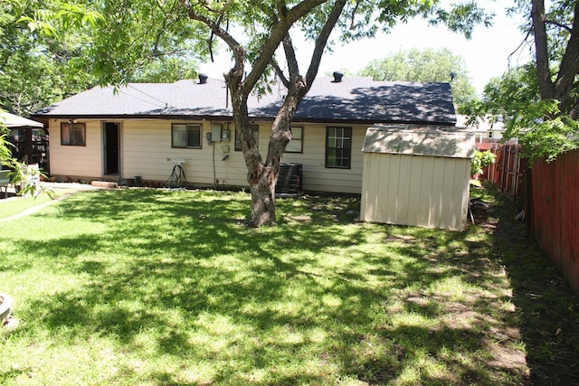rear view of house with an outdoor structure, central AC, fence, a shed, and a yard